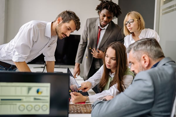 This is an image of people looking at a tablet screen in a boardroom