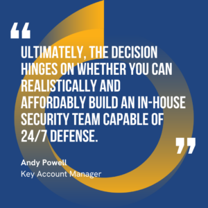 The graphic visually represents a quote by Andy Powell that says, "Ultimately, the decision hinges on whether you can realistically and affordably build an in-house security team capable of 24/7 defense."