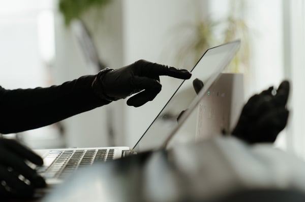 This is an image of a gloved hand pointing at a laptop screen 