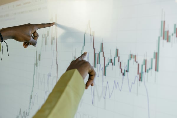 This is an image of two fingers pointing at a graph on a screen