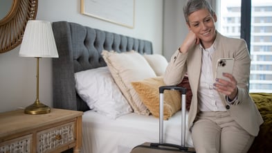 Business woman sitting on a hotel bed talking on a video call
