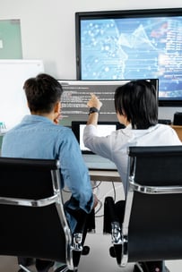 This is an image of two men analysing code on a monitor