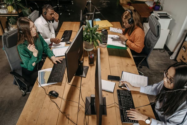 This is an image of contact centre agents working at a shared desk.