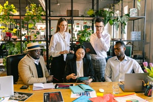 This is an image of people gathered at a board table and looking at a tablet. 