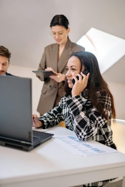 This is an image of a woman in an office talking on the phone.