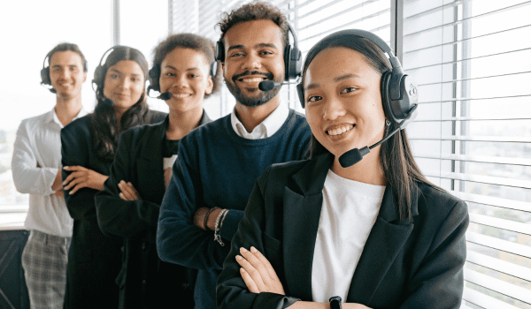 This is an image of call centre agents standing in a row and smiling at the camera.