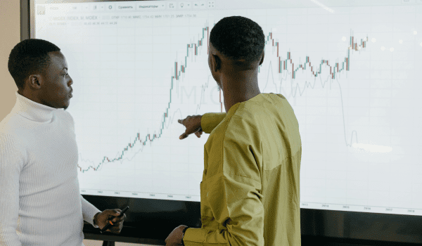 This is an image of a man pointing to a graph on a screen.