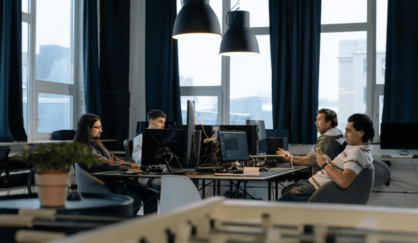 This is an image of people working in an office at a shared desk.