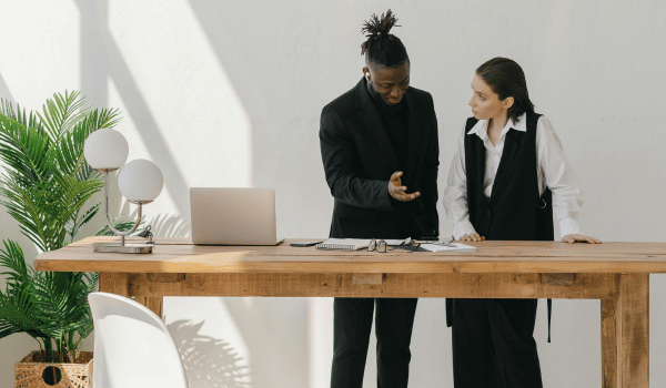 This is an image of two people reviewing and discussing some documents on a table.