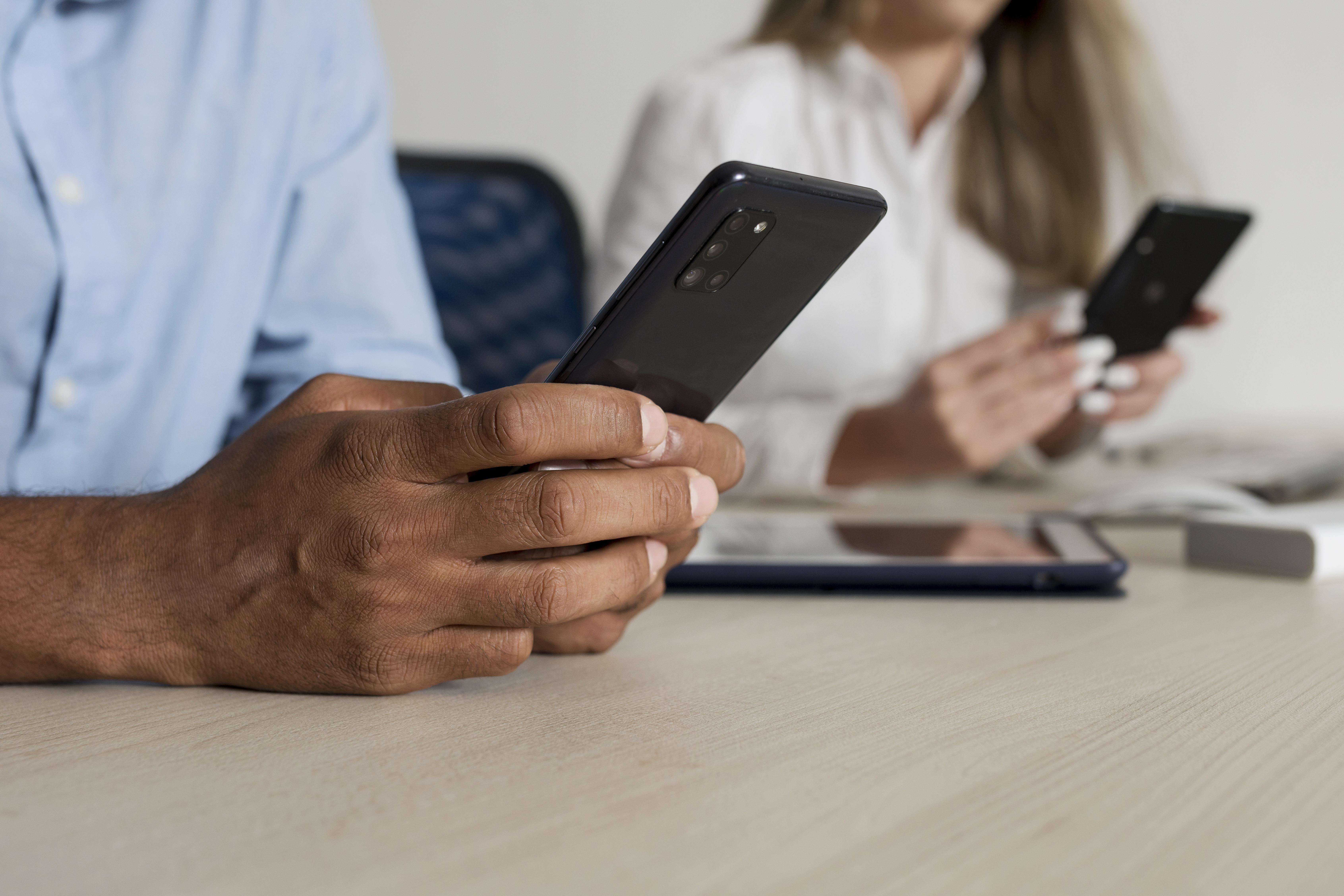 This is an image of a man and woman's hands holding phones.