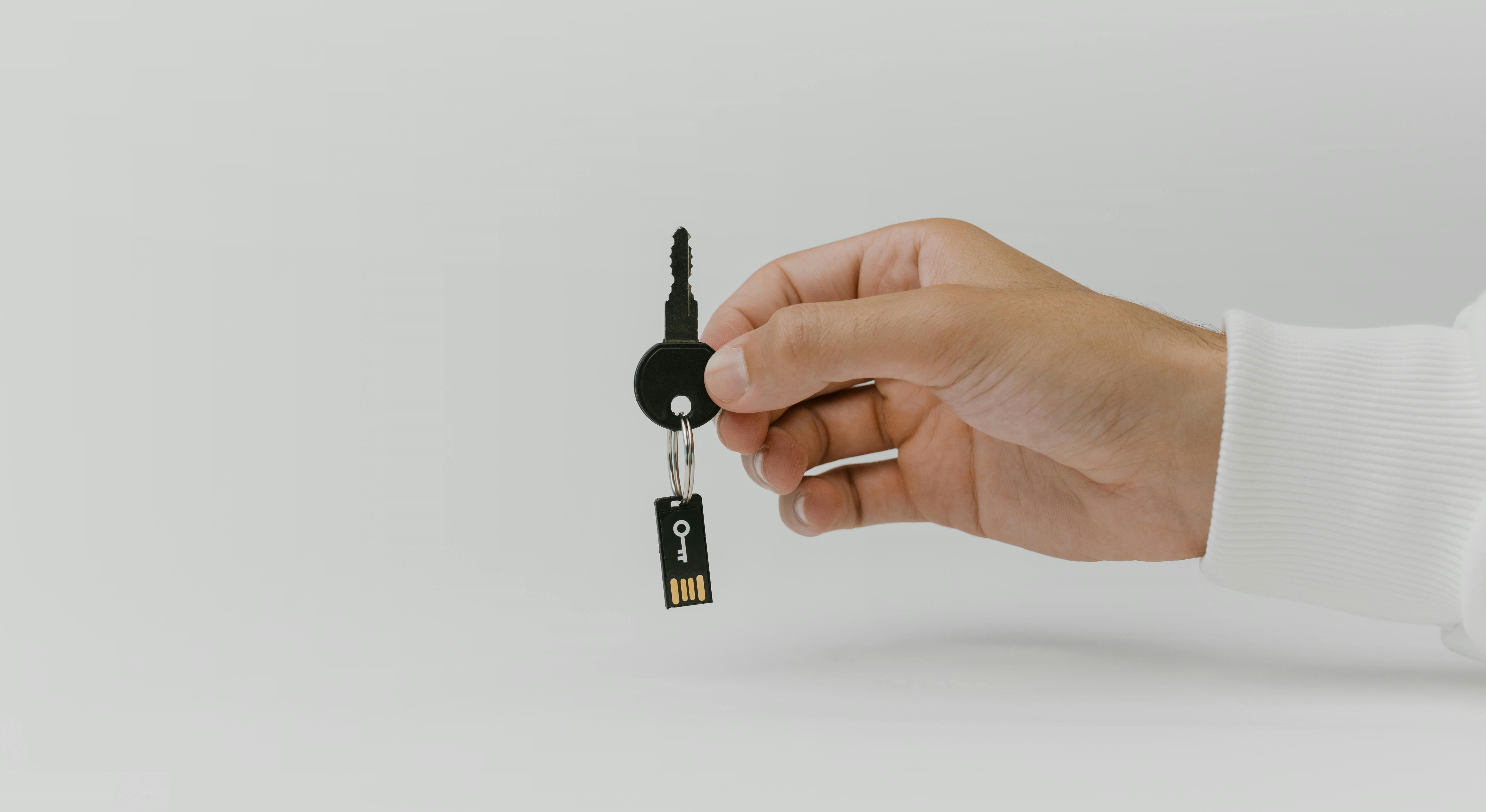 This is an image of a man's hand holding a key with a USB attached.
