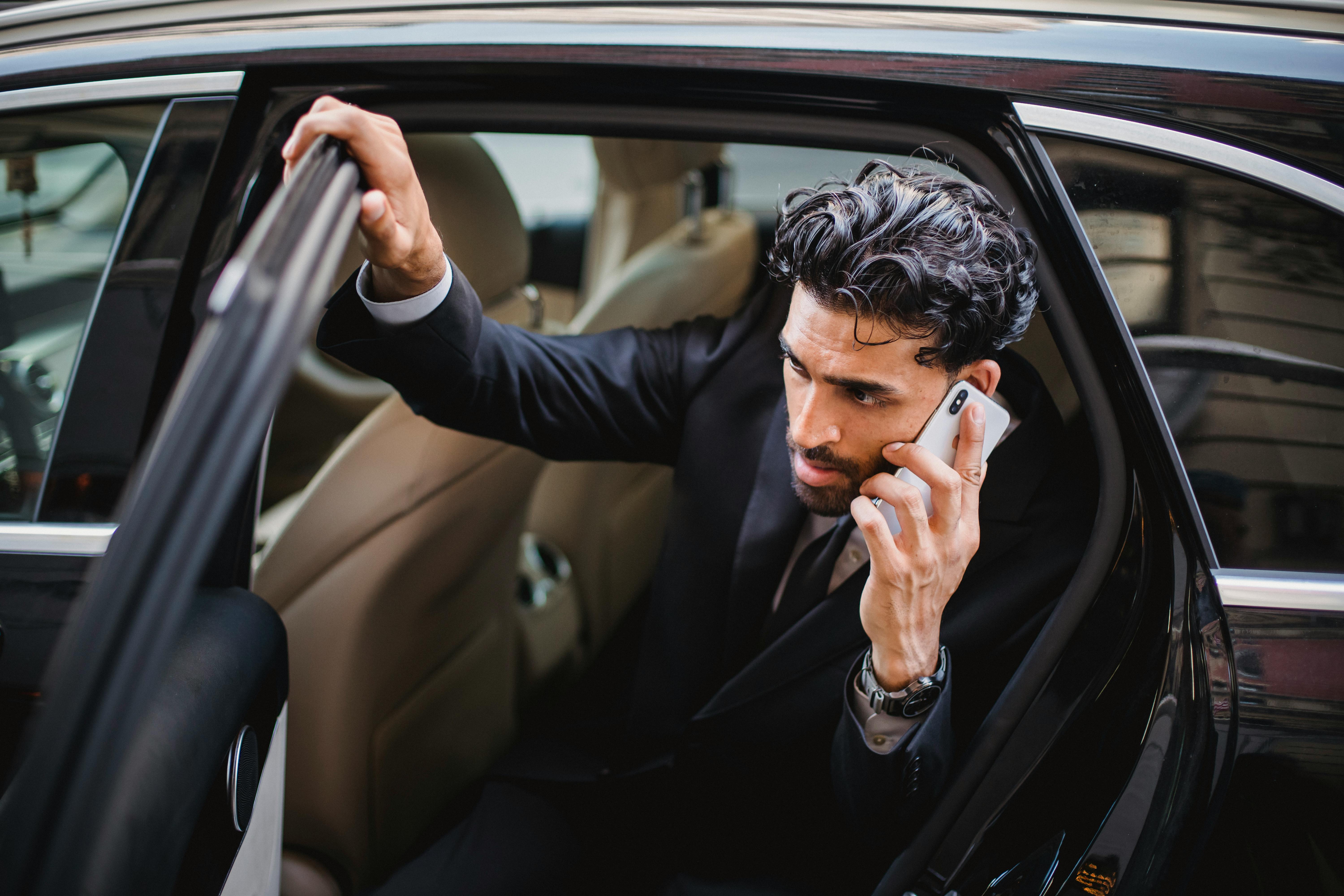 This is an image of a man on the phone getting out of a car.