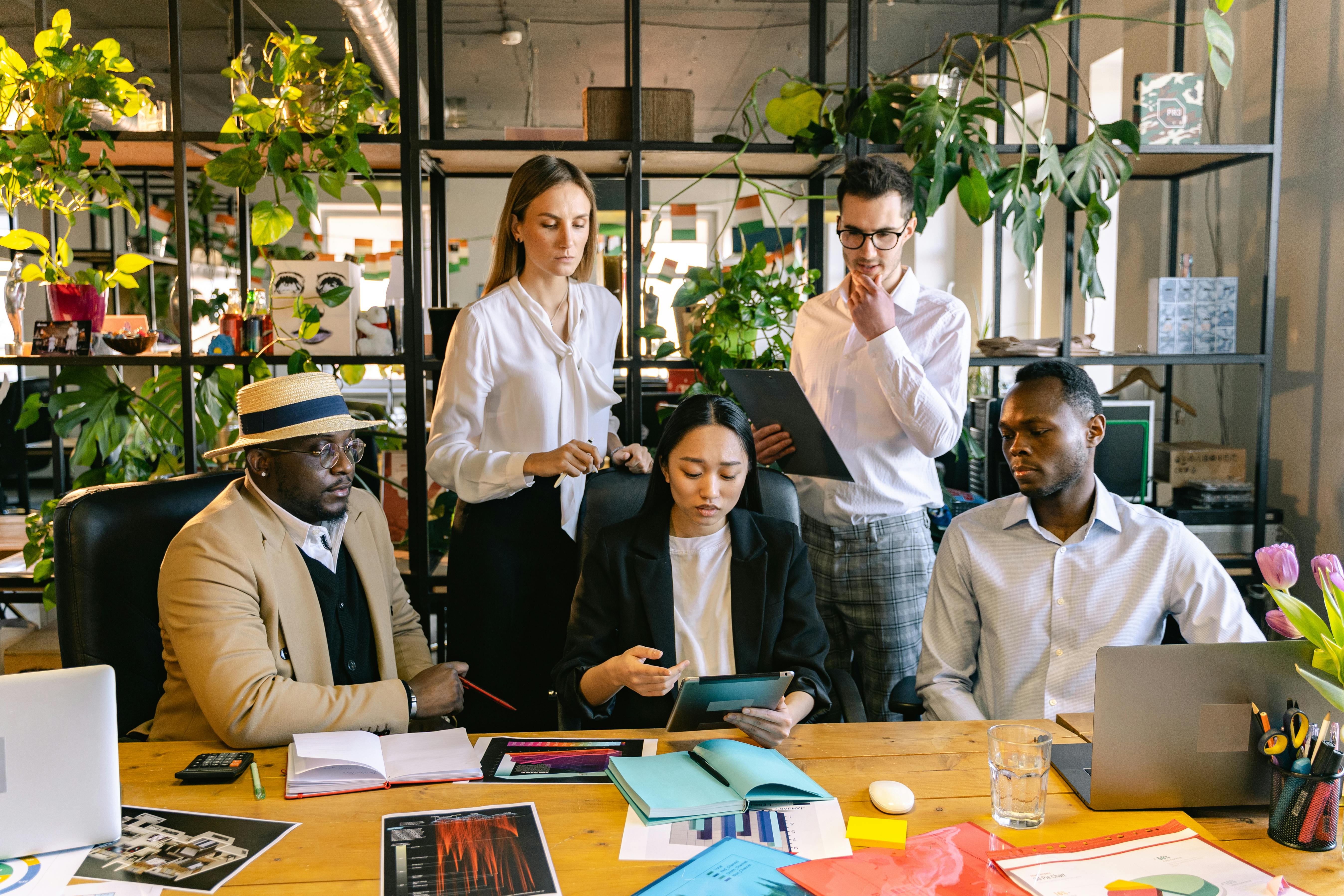 This is an image of people gathered at a board table and looking at a tablet.