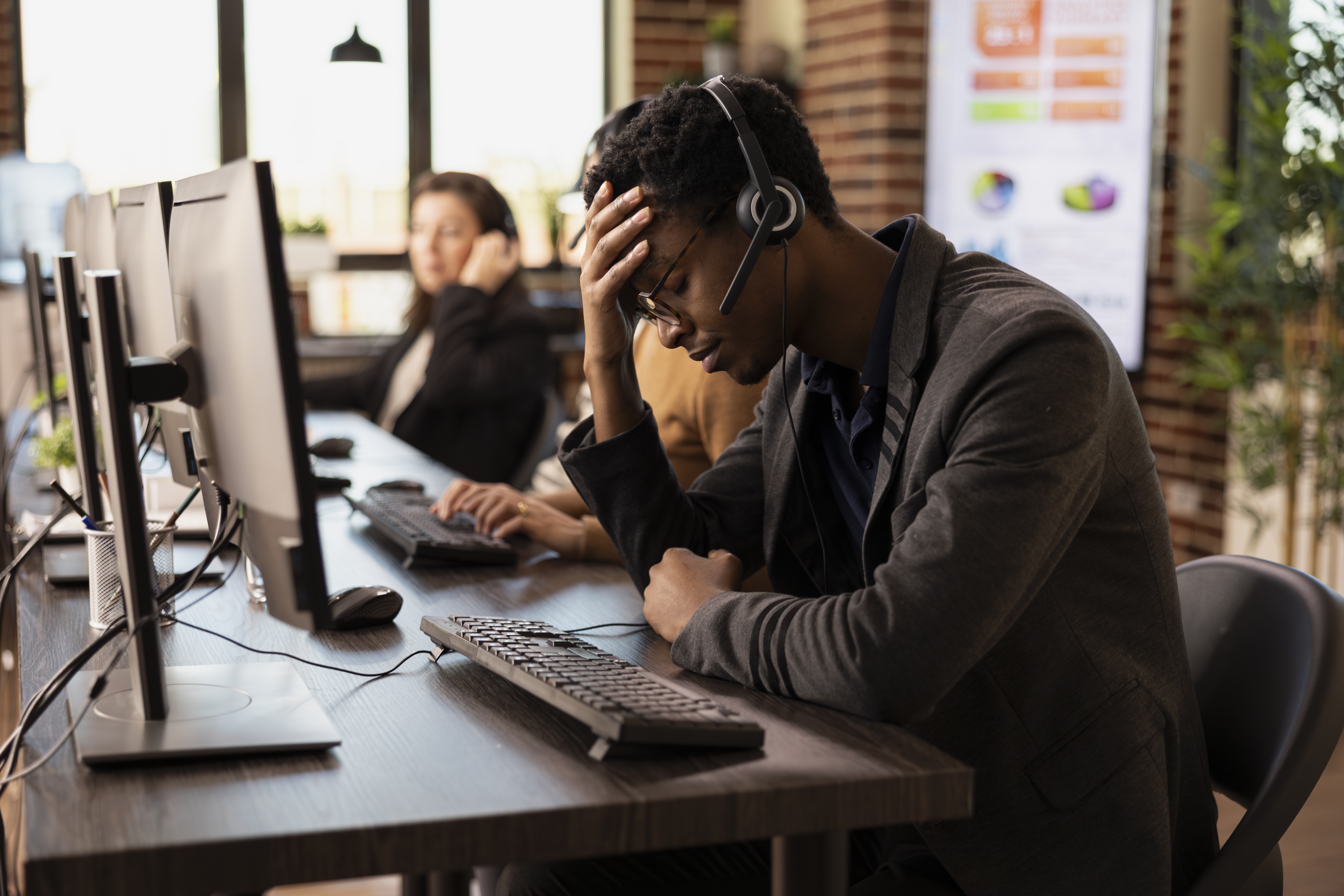 This is an image of a frustrated call centre agent holding his head in his hand.